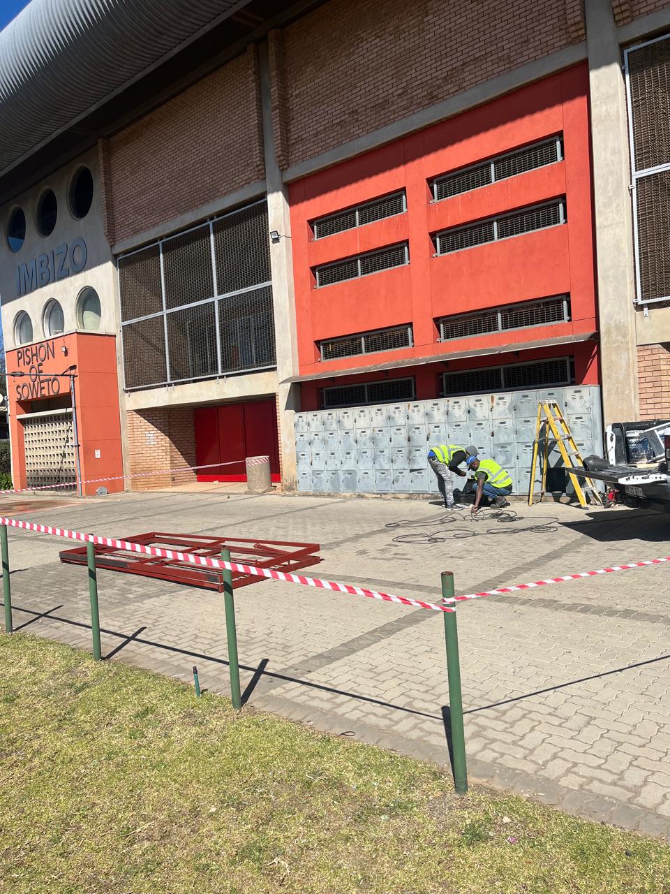 Exterior work area at a public building with safety tape and equipment